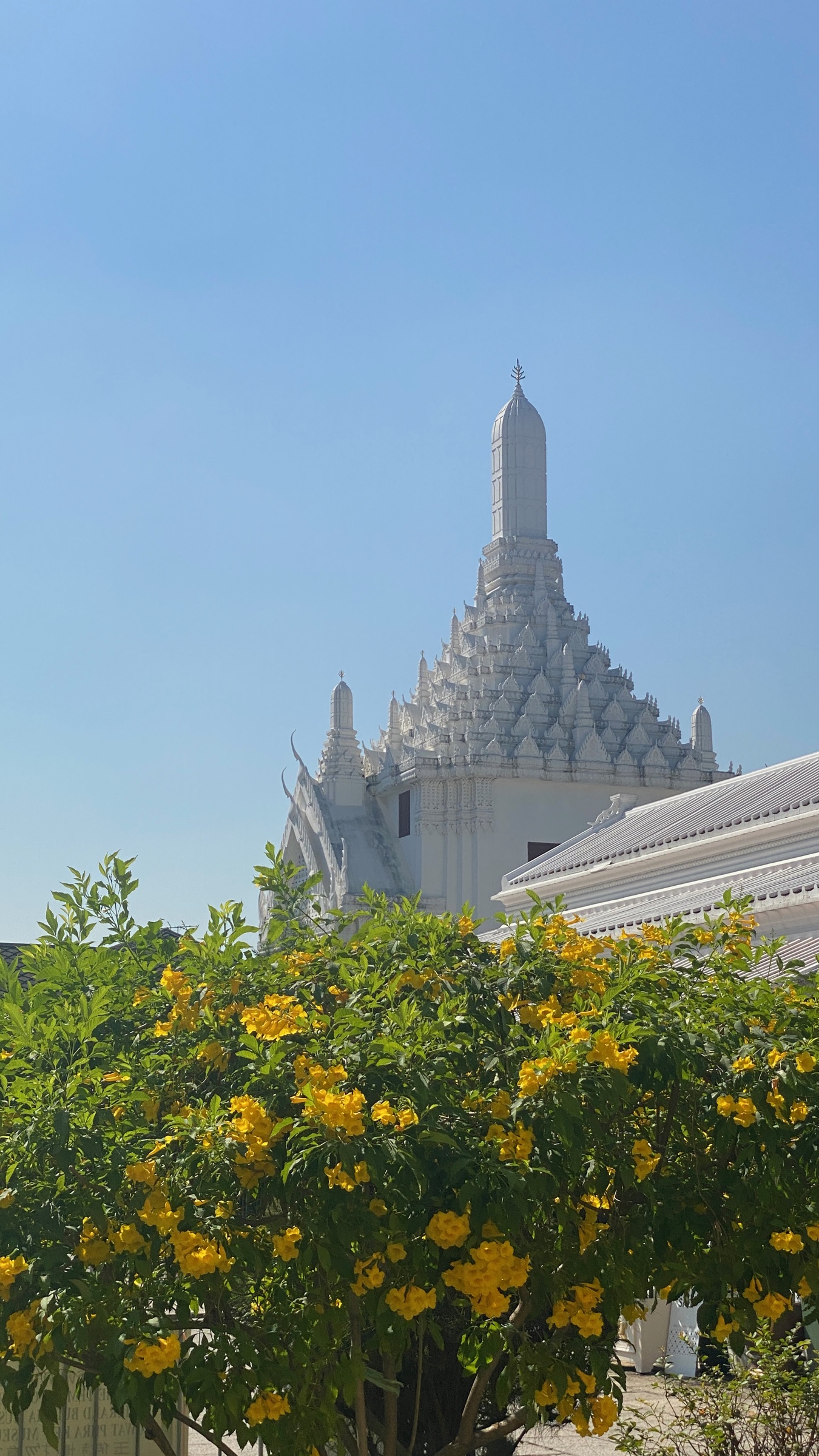 Temple spires and yellow flowers at the Grand Palace in Bangkok